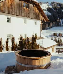 Wooden cold plunge is surrounded by snow outside Ostí Vedl.