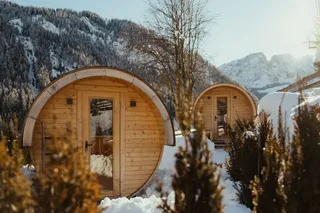 Two wooden barrel-shaped sauna in a snowy mountain landscape